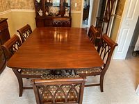 Overview of the rectangular hardwood table with cherry finish and six matching upholstered chairs arranged around it
