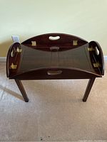 Front view of the folded wooden coffee table showing the dark brown finish and a curved handle in the center on the front panel.