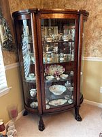Front view of brown wood china cabinet showing curved glass front doors, arched top molding and interior display shelves
