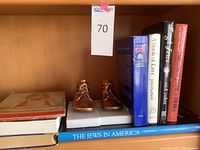 Books and copper baby shoes on a shelf, showing titles and display stands