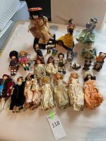 Photo showing a laid-out collection of predominantly vintage dolls and figurines in traditional and storybook clothing, various sizes and ethnic styles.