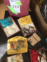 Several open boxes displaying assorted costume jewelry and storage pouches