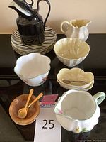 Overview of milk pitchers, dessert plates, and various salt/sugar bowls with spoons arranged on black surface.