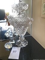 Photo showing tall crystal decanter with intricate cut patterns on a mirror surface, alongside the number '1' crystal figurine and turtle figurine.