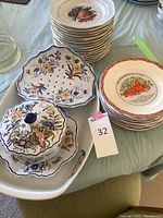 Stack of Gien France dessert/fruit plates and other plates including a Decor Rouen condiment bowl with lid decorated with blue and orange floral patterns.