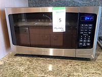 Front view of the microwave oven showing digital display and keypad interface with blue timer readout