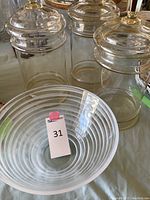 Photo showing three large clear glass canisters with decoratively cut lids featuring faceted knobs, and a swirl-patterned frosted glass Salviati serving bowl.
