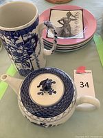 Pink Nieman Marcus dessert plates stacked with a ceramic teapot and ceramic pitcher behind
