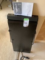 Another angle of electric trouser press upright with manual on top, showing power cord and item details.