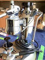 Side view of chrome machine with portafilter inserted on drip tray
