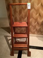 Front view of the wooden three-tier step stool showing slatted steps and tall vertical side supports.