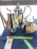 Three silver pots arranged on blue cloth showing overall condition and style.