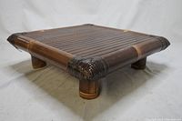 Angled side view of the bamboo tea table showing the slatted top surface and woven corners.