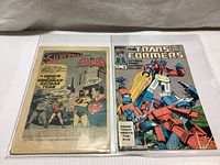Two comics side by side: 1958 DC World's Finest Comics interior page from issue #94 with Superman and Batman story, and 1986 Marvel Transformers issue #12 full color cover.