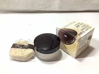 Photo of the powder jar with black lid, velour puff sealed in plastic, and product box.