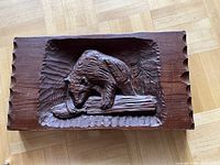 Front view of the carved wood panel showing bear fishing scene with scalloped edges.