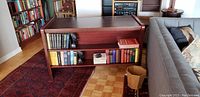 Side view of mahogany bookshelf side table showing two shelves with books and a vintage look.