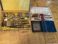 Full view of the complete cutlery set with yellow satin lining, the carving set with stag handles in white satin box, unopened guestbook with blue cover, and a silver-plated tray.