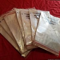 Photo showing multiple resealable clear poly bags stacked, displaying the red resealable adhesive strip along the top edge.