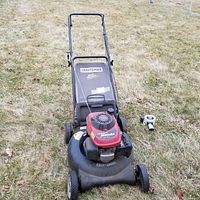 Front overview of black Craftsman lawn mower with red Honda engine and four wheels, shown on grass.