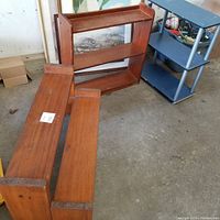Photo showing two wooden three-tier shoe shelves and one blue plastic/metal shoe shelf, all with visible wear.