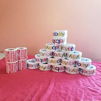 Wide view showing all rolls of eBay packing tape and fragile sticker tapes arranged on a red cloth surface.