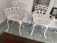 Two white metal patio chairs side by side on tiled floor