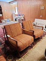 Front view of both armchairs on rug showing wood frames, woven cane arms and upholstered seats