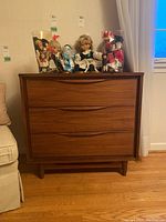 Front view of wooden dresser with three drawers and integrated curved pulls