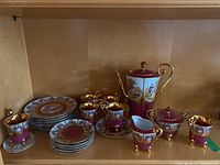Full service displayed on shelf: coffee pot center, sugar bowl, creamer, stacks of dessert plates, six cups on saucers