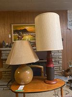 Both lamps on a small oval table in front of a stone fireplace and wood paneling wall, showing overall size and style.