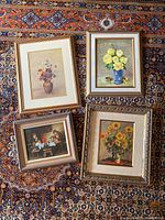 Four framed artworks laid on patterned rug, showing original painting and three prints