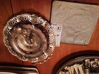 Silver-plated pierced decorative bowl with scalloped lattice edge and rose-pattern ladle next to closed spoon case