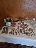 Full view of silver plated serving pieces, cutlery and porcelain dishes on table