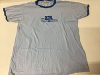 Front view of vintage Stanfields XL single stitch ringer T-shirt light blue with navy collar, sleeve trim, and center chest graphic.