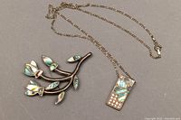 Photo showing the sterling silver chain necklace with rectangular pendant and the branch-shaped brooch with abalone shell inlays.