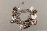 Full view of the sterling silver charm bracelet showing multiple attached charms including teapot, coin, and turtle.