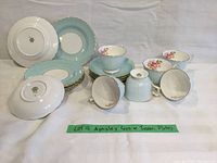 Full set showing 6 Aynsley teacups, Tuscan blue saucers and plates arranged on white fabric background