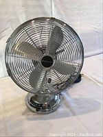 Front view of chrome Bionaire table fan showing grill and blades
