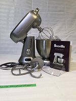 Front view of mixer with bowl, attachments and manual