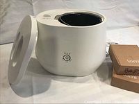 White Lomi composter body with lid removed showing black inner bucket and power cord; two cardboard refill boxes visible on right.