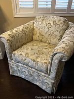 Front view of the floral upholstered arm chair showing the armrests, seat cushion, and back cushion in light beige fabric with floral pattern.