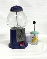 Metal and glass gumball machine with clear globe and blue base alongside a vintage Boss chopper with teal lid and black knob
