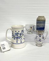 Full view of the four items: Turi-design water pitcher with Lotte pattern, glass milk bowl, glass sugar bowl, and blue hand-turned vase arranged on white blocks