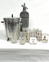Full view of the set including ice bucket, seltzer bottle, and glasses with star motifs on a white background.