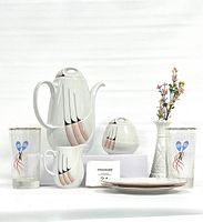 Full lot showing the retro tea set (teapot, sugar bowl, creamer), two printed glasses with blue heart floral design, two floral side plates, and a white milk glass vase with pink flowers arranged neatly on a white background.