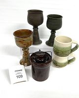 Photo of three handmade pottery goblets, two ceramic mugs, and a cheese crock with lid and wire handle.