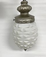 Close-up image of the white textured glass shade with ornate silver finish metal fixture at top and bottom