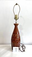 Front view of tall vintage brown ceramic table lamp with brass socket and harp, showing detailed square pattern around the ceramic body.