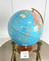Full view of the vintage George F. Cram Company Imperial globe showing the Pacific Ocean and parts of North America with wooden base and brass-colored meridian.